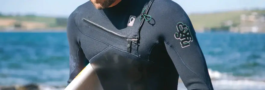 A man wearing a C-Skins Rewired wetsuit at the beach