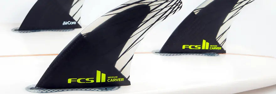 A close up of FCS II Carver fins in a surfboard