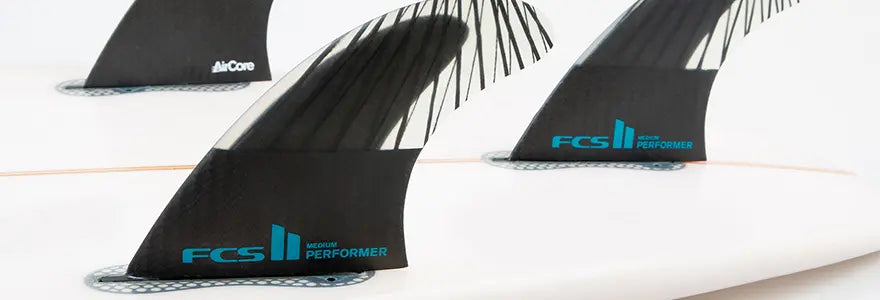 A close up of a set of FCS II Performer fins in a surfboard