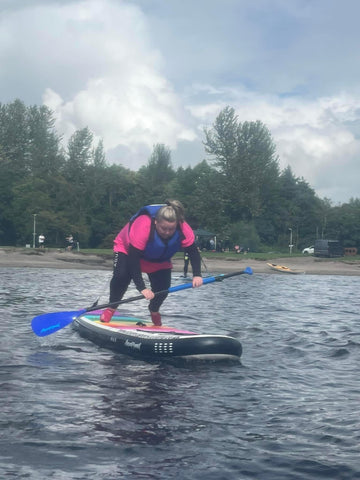 female in pink top on paddleboard falling forward towards the water
