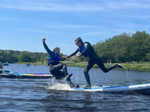 two males falling off the side of a paddleboard