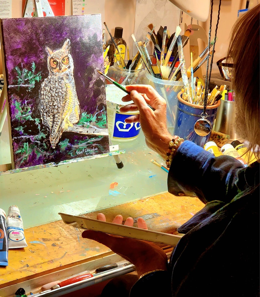 Canadian artist Robert Lariviere working in his studio on a painting of an owl.