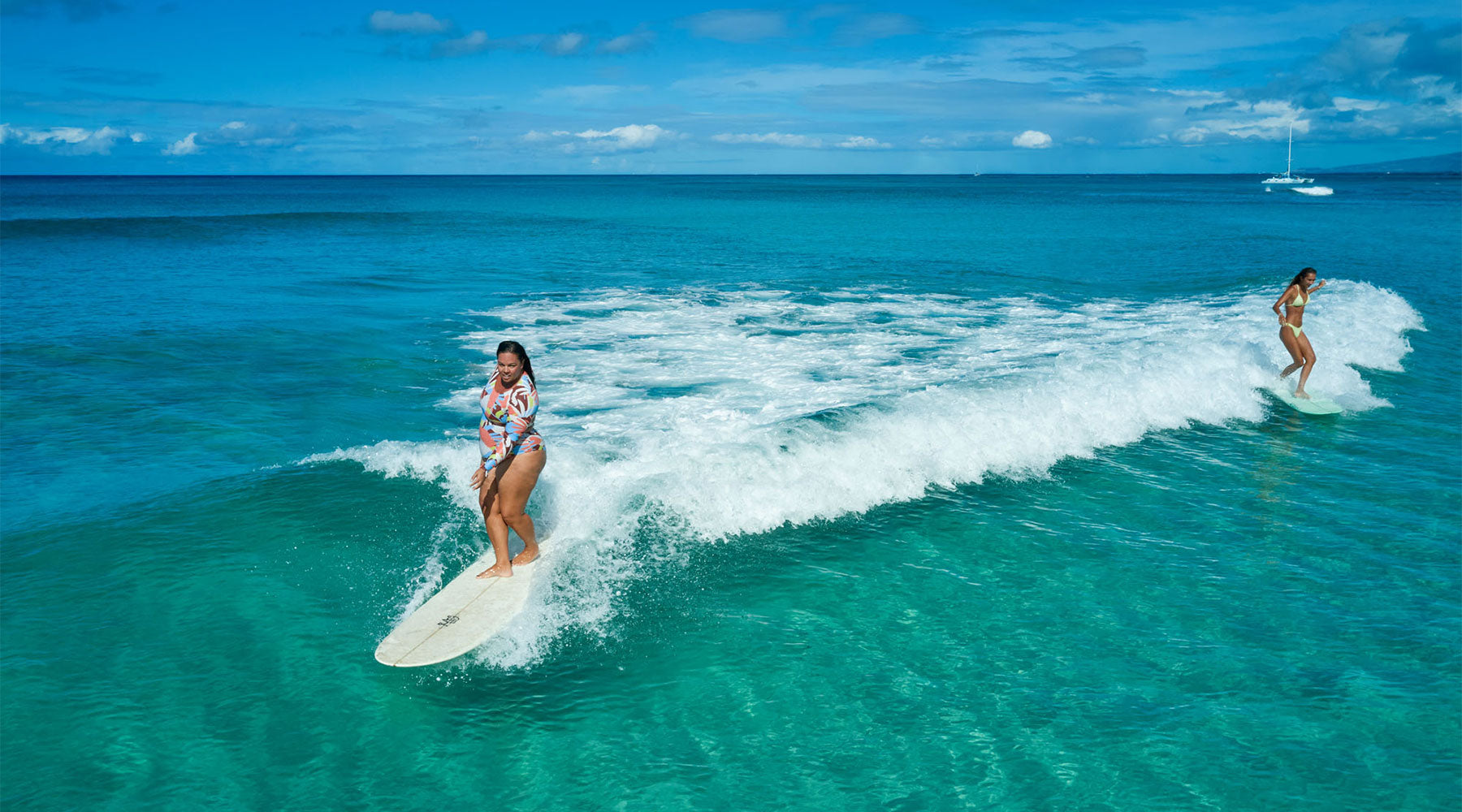 Girls surfing together on a wave wearing Roxy swimmers