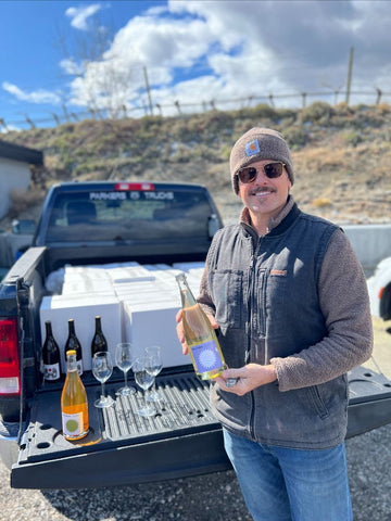 Anthony Buchanan stands at the end of his pick up truck, proudly showing off his 2022 wines