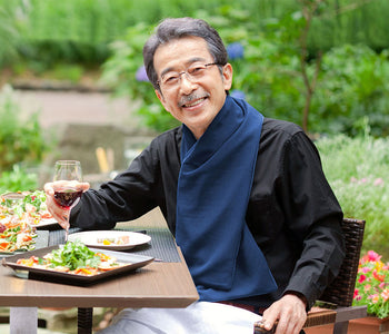 Older man eating a meal with wine on a patio while wearing the protective scarf bib.