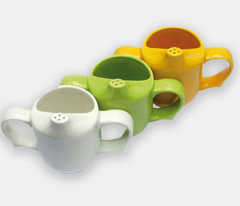 Angled top view of a white, a green, and a yellow mug, all designed to maintain dignity during mealtimes.
