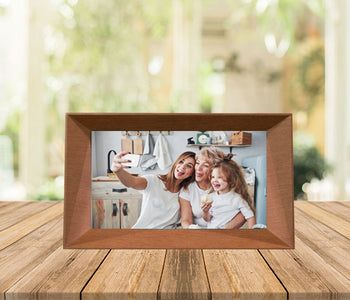 Familink 7-inch digital frame placed on a table showing a woman with her daughter and granddaughter taking a selfie.