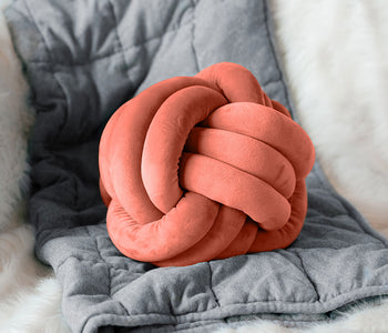 Coral calming sensory cuddle ball laying on blankets.