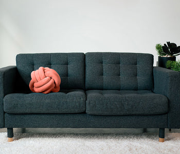 Soft coral sensory cuddle ball laying on a couch.