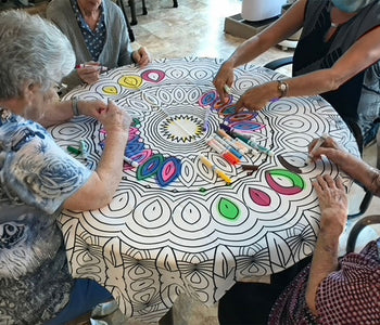 A group of elderly residents coloring a Bimoo washable mandala tablecloth.