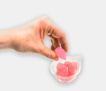 A hand taking a raspberry hydrating water and electrolyte jelly drop from a snack pot.