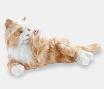 The orange companion cat designed for people living with dementia, on its side, with its paw lifted.