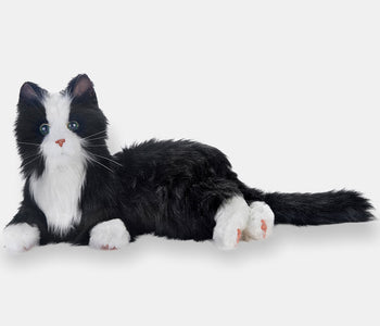 The tuxedo companion cat from Joy for All, for people living with dementia, laying on its side.