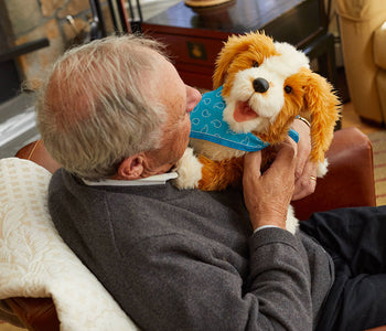 Older Man interacting with the freckled pup from Joy for All.