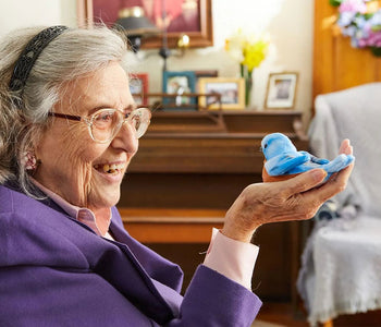 An older lady holding and interacting with the blue walker squawker bird companion.