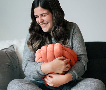 Woman hugging the coral and calming sensory cuddle ball.