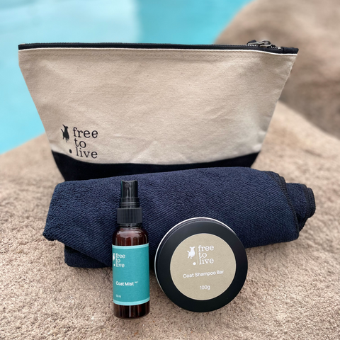 Image of travel pack by pool. Shows bag, black towel, Coat Shampoo Bar in a tin and Coat Mist No.1