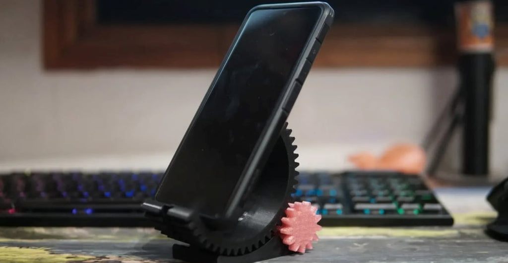 A sleek 3D printed phone stand with a phone displaying Co Print's logo.