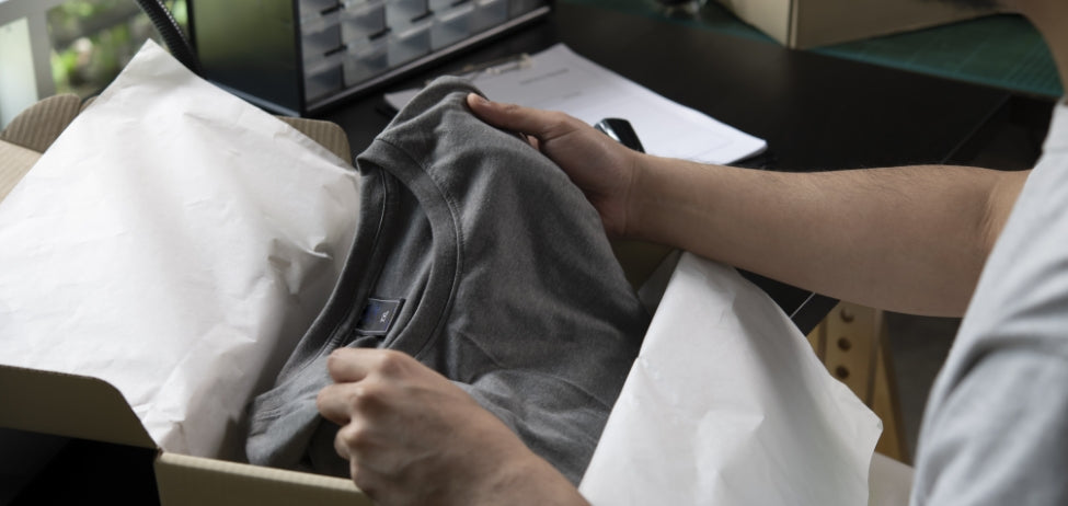 A person opening a t-shirt they bought online.