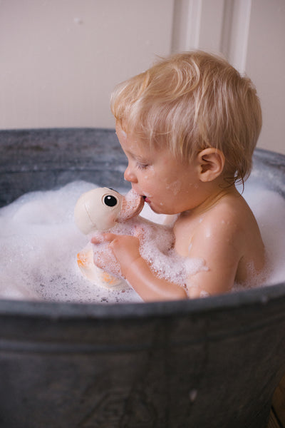 Ein kleiner Junge spielt mit einer Kawan Badeente von HEVEA in einer Badewanne