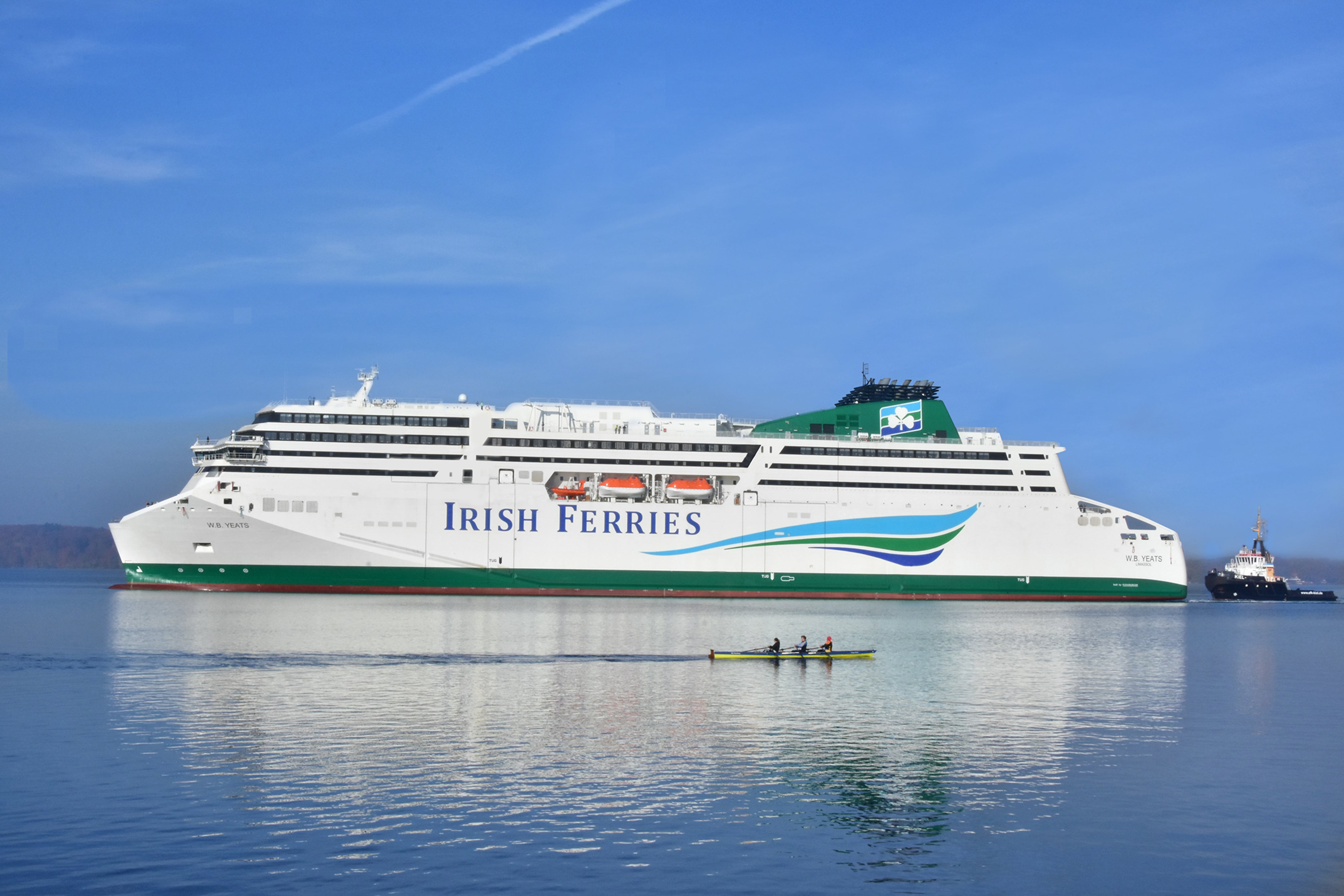 A large ferry labeled 'Irish Ferries' on calm water with a rowboat in the foreground.