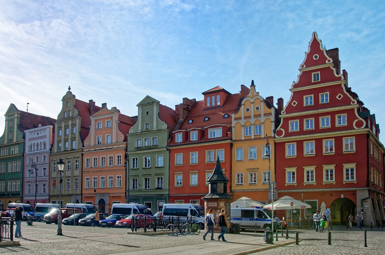 Colorful European-style buildings on a sunny day with people and parked cars.