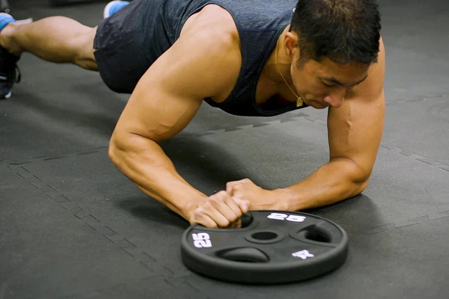 A man doing weight plate exercise, plank plate switch