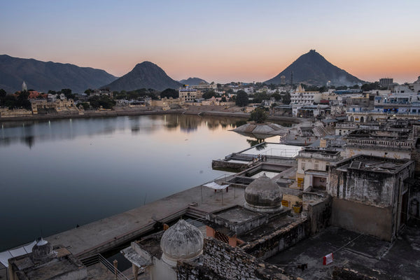 Paesaggio città indiana vicino a specchio d'acqua con montagne sullo sfondo.