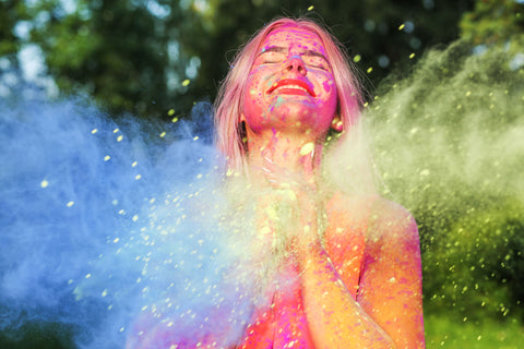 Una ragazza viene ricoperta da polveri colorate durante i festeggiamenti di Holi.