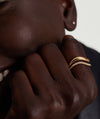 Close-up of a hand showcasing the Dôme Figure Pavé Diamond Ring, featuring sleek curves and pavé diamonds set in 14k gold.