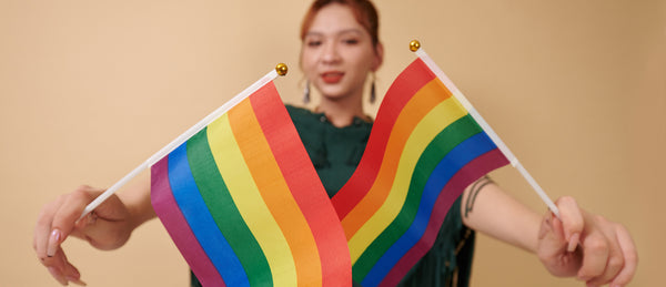 Blurred woman holding two rainbow flags