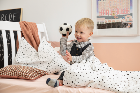 a young child plays with a ball on a bed