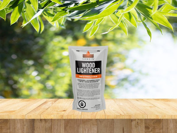 Le sachet de produit Sansin Wood Lightener se retrouve sur un deck en bois. En arrière plan nous voyons une belle forêt verdoyante par une belle journée d'été ensoleillé.