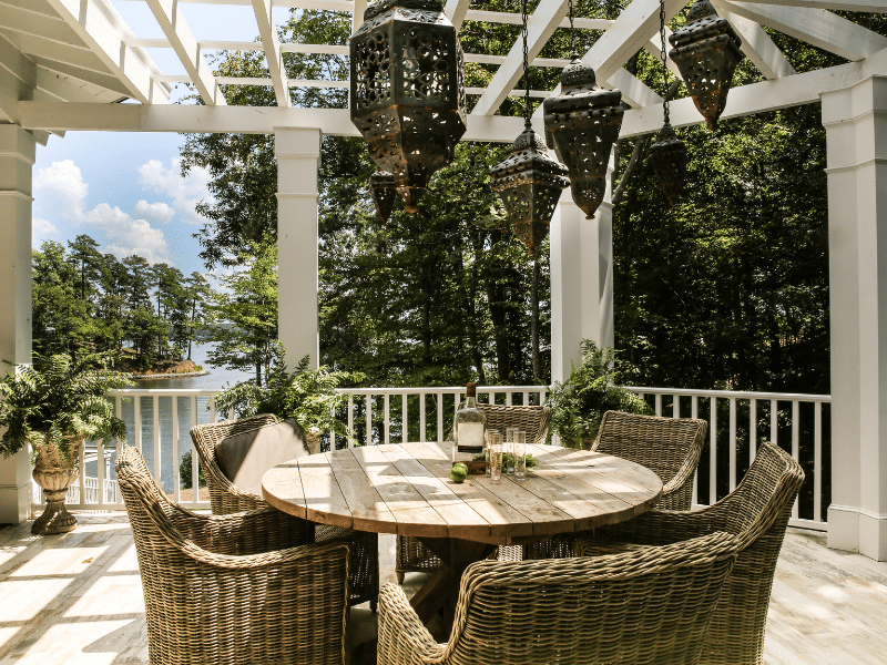 Merveilleuse terrasse en bois sur le bord de l'eau avec beaucoup d'arbres. Il y a une table a manger en rond avec quatres chaises et la terrasse possède une pergolas.