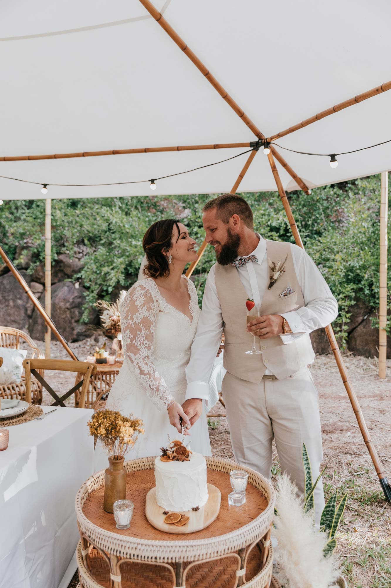 sand and terracotta wedding decor with dried flowers, bride and groom standing in front of basket table in a teepee for a festival style wedding