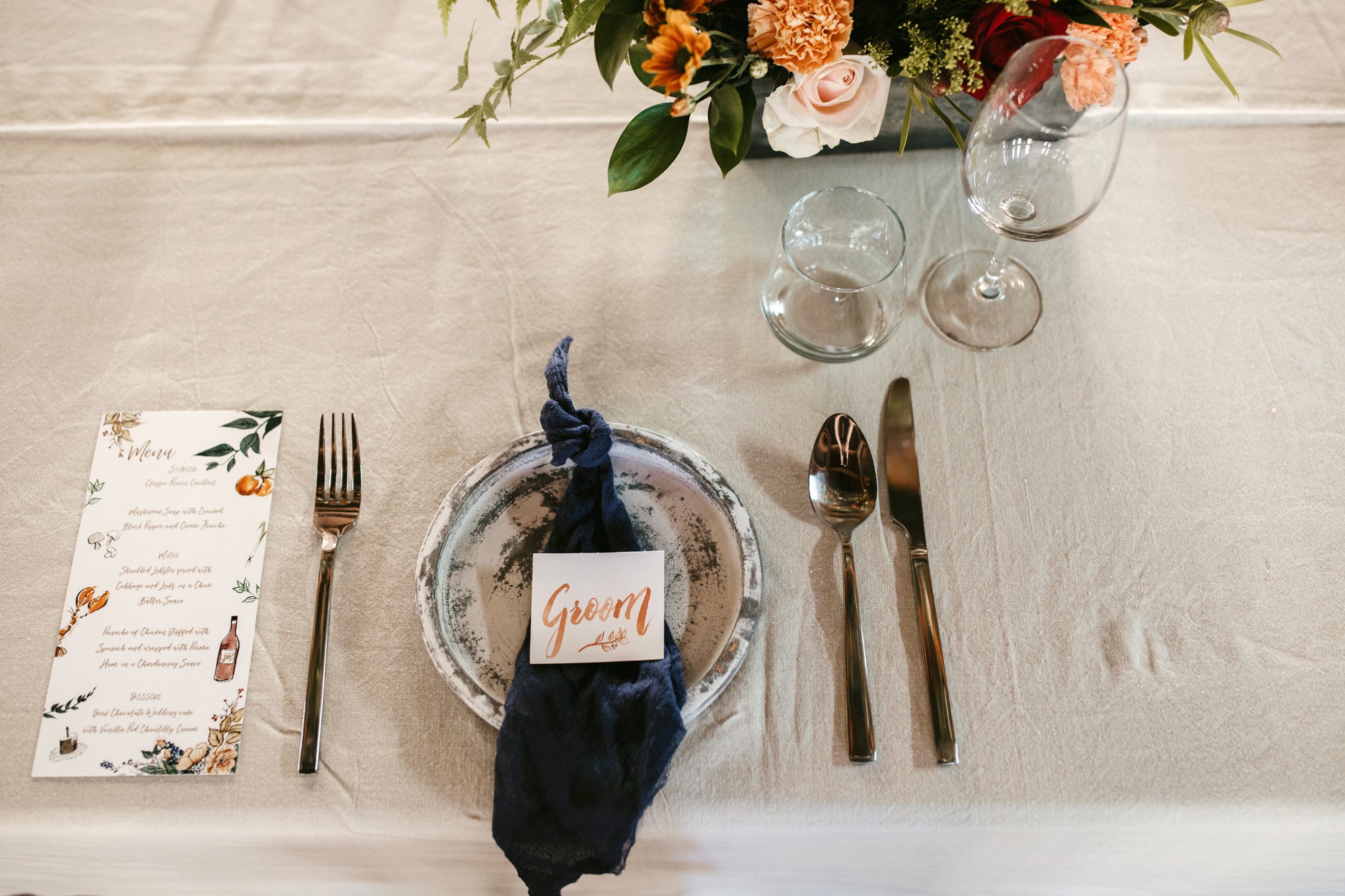 Pottery place setting at a wedding with navy linen and watercolour place cards