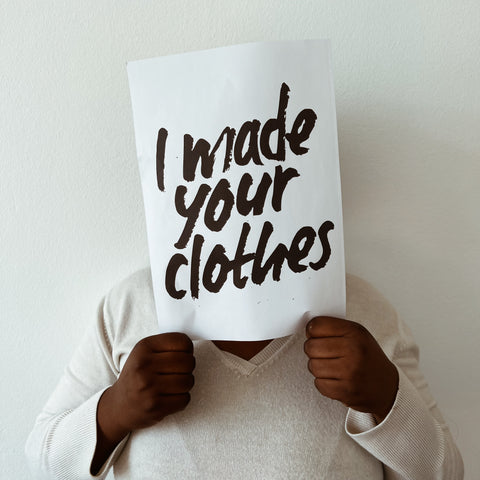 Person who suffered from exploitation shows a "I made your clothes" sign.