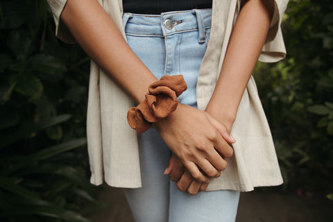 Women is wearing a brown scrunchy on her arm.