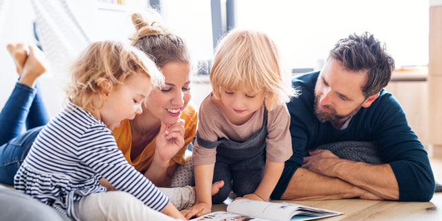 Mutter und Vater lesen ihren beiden kleinen Kindern etwas vor.