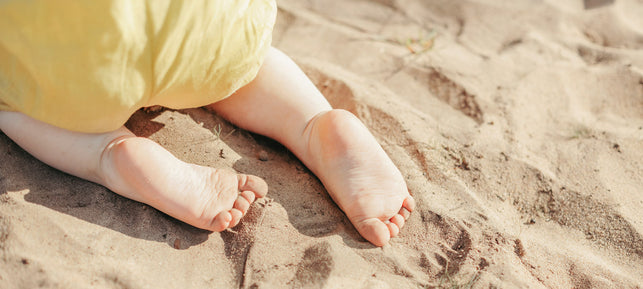 Baby krabbelt im Sand 