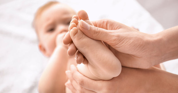 Baby bekommt von Osteopathen den Fuß massiert.