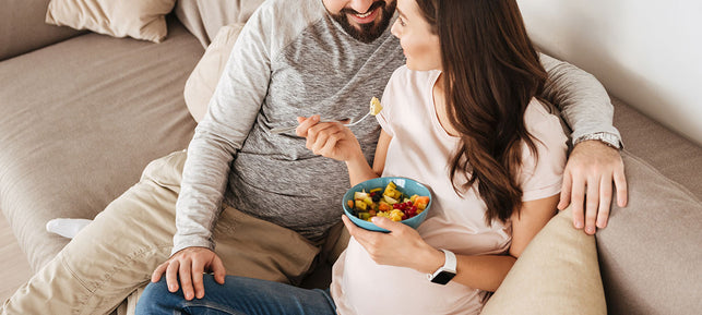 Mujer embarazada disfruta de una comida saludable junto a su pareja