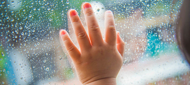 Bebé mirando por la ventana en un día de lluvia