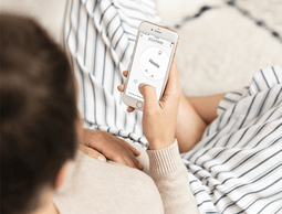 Schwangere Frau nutzt LILLYDOO-App auf dem Smartphone