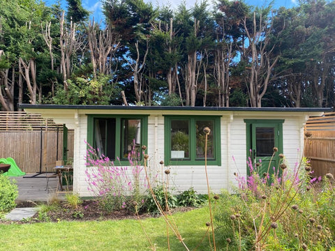 log cabin painted white with a green trim 