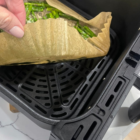 Lifting a used air fryer liner from air fryer basket