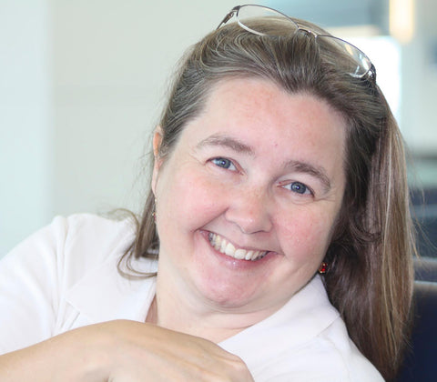 Jackie Hird leaning on the back of a chair smiling