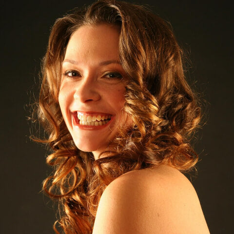 Woman with curly hair smiling after using a Solid bar Company shampoo bar
