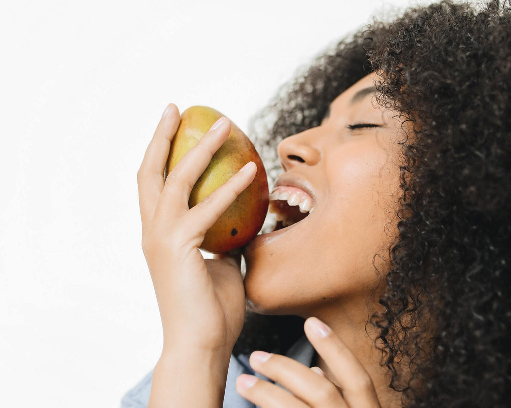 A woman is eating a fruit to have healthier skin