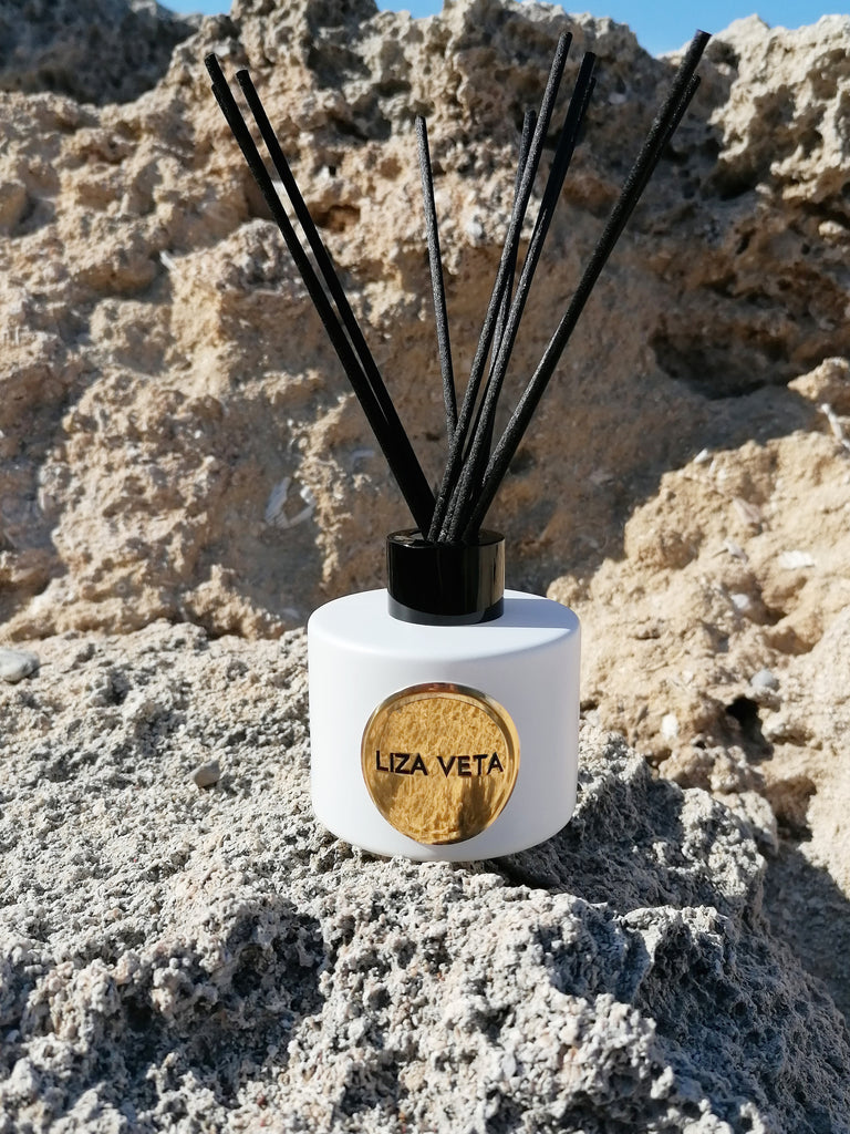 This is white aromatherapy reed diffuser located on a rock outside. This image is related to self care during spring.